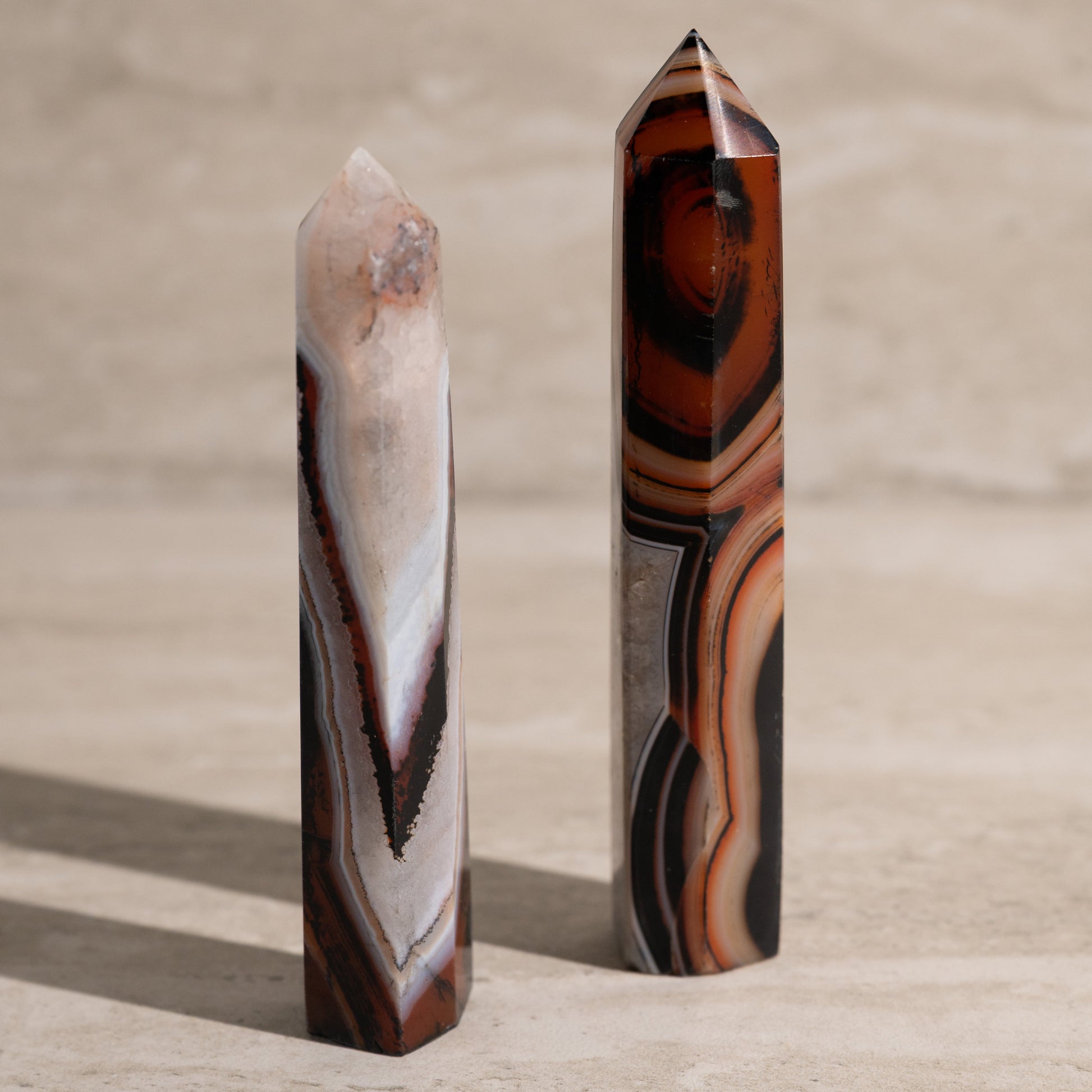 Two agate crystal points on a beige surface