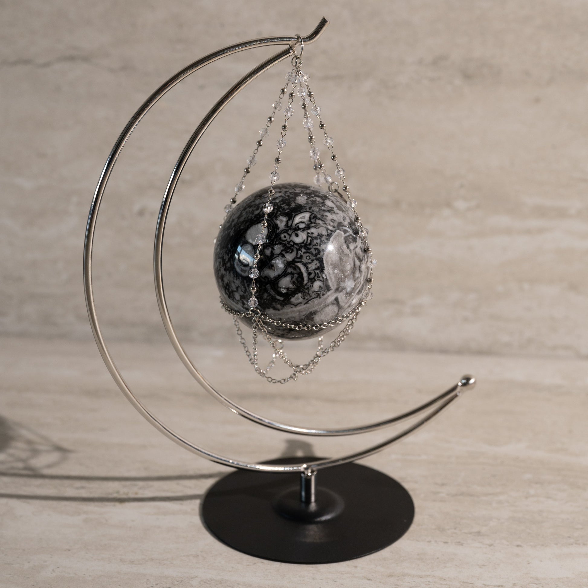 Decorative sphere on a metal stand against a neutral background