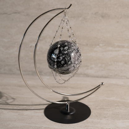 Decorative sphere on a metal stand against a neutral background