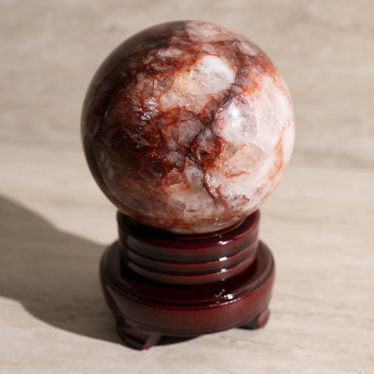 Decorative stone sphere on a wooden stand against a neutral background