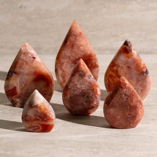 Five teardrop-shaped stones on a beige surface