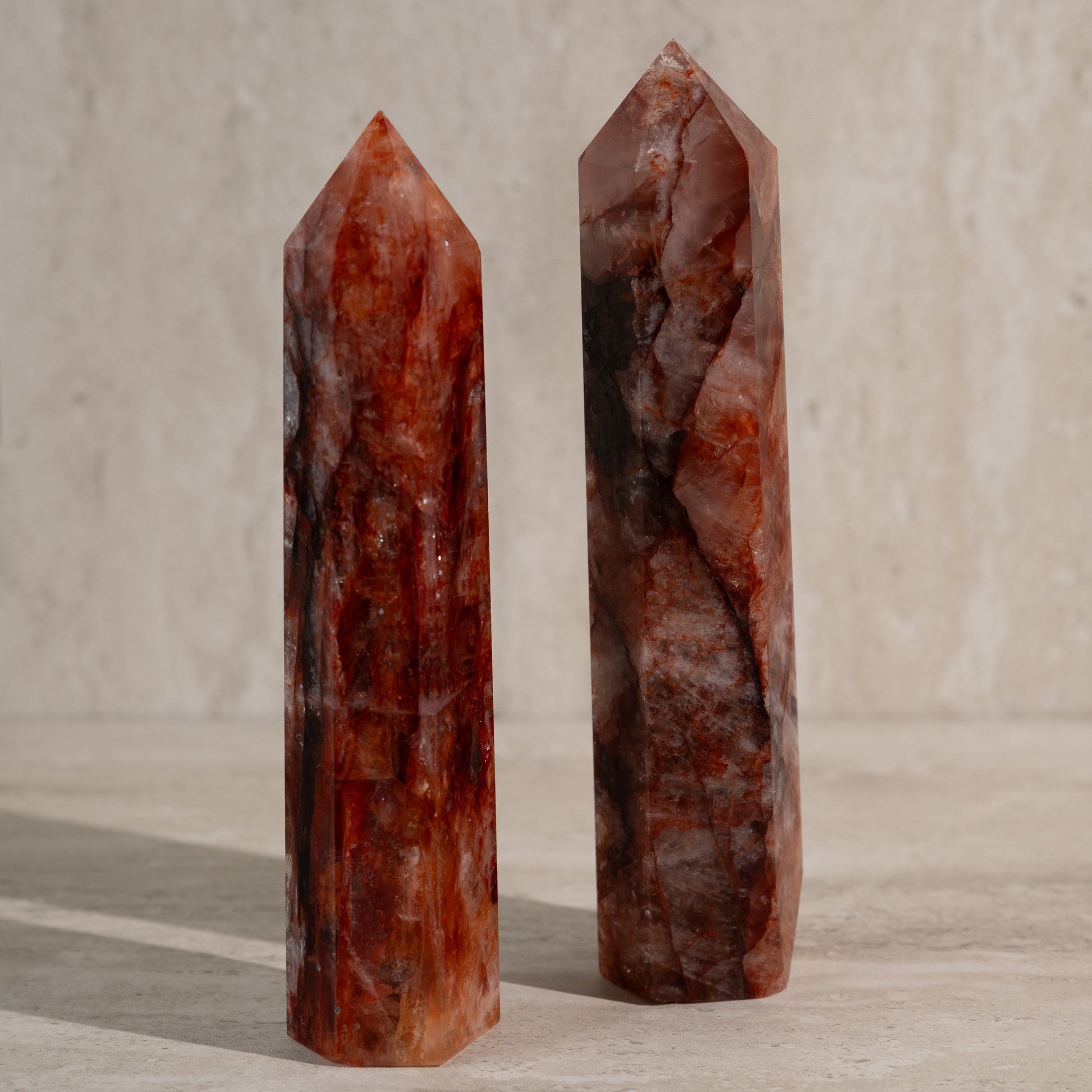 Two polished red crystals on a wooden surface with a neutral background