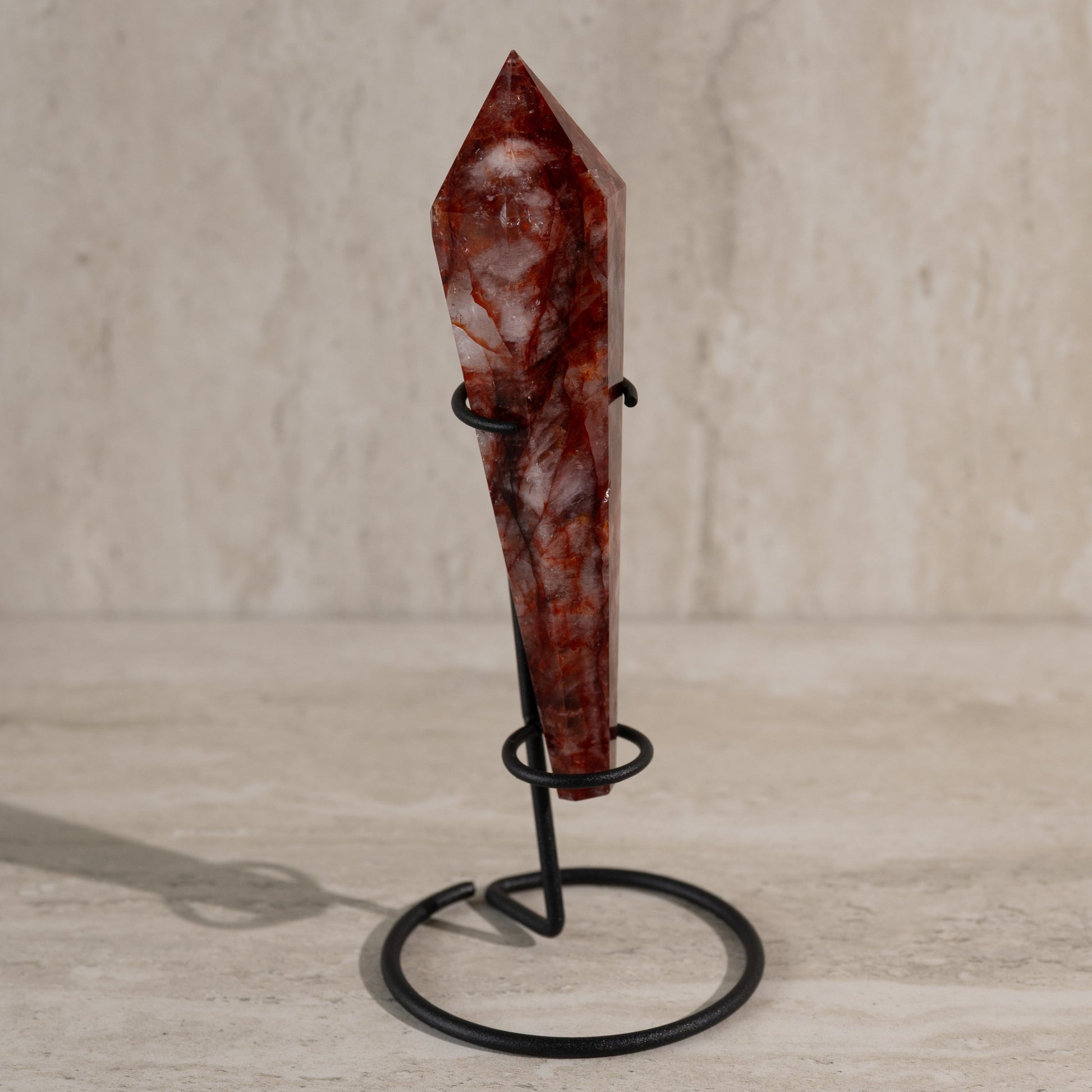 Red crystal on a black stand against a neutral background