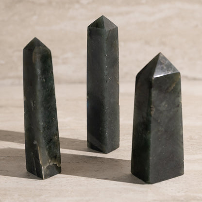 Three black stone obelisks on a beige surface