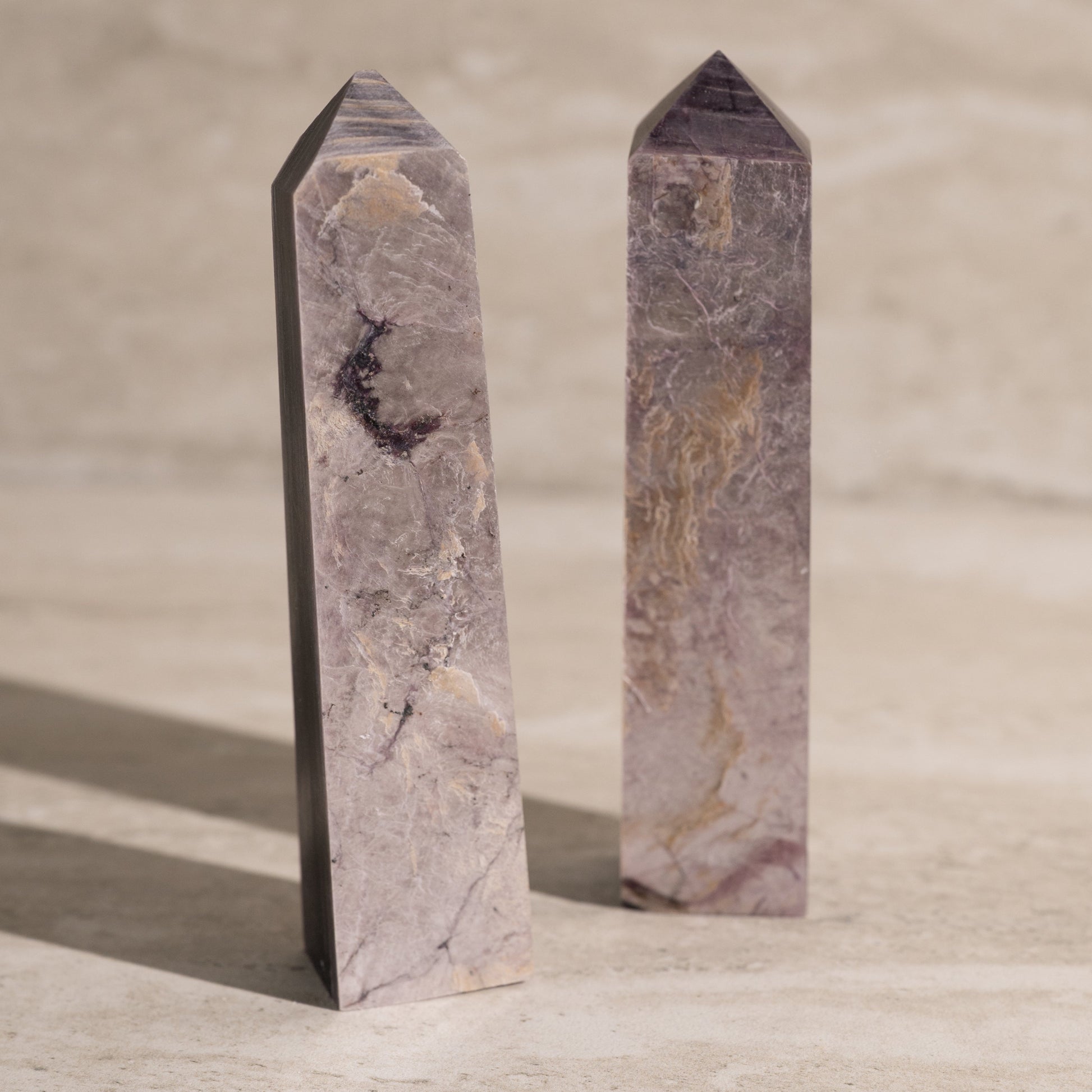 Two polished stone obelisks on a neutral background
