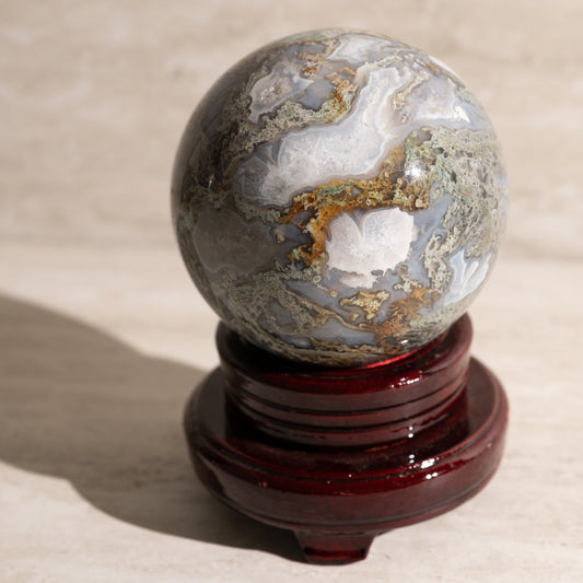Marble-like sphere on a wooden stand against a beige background