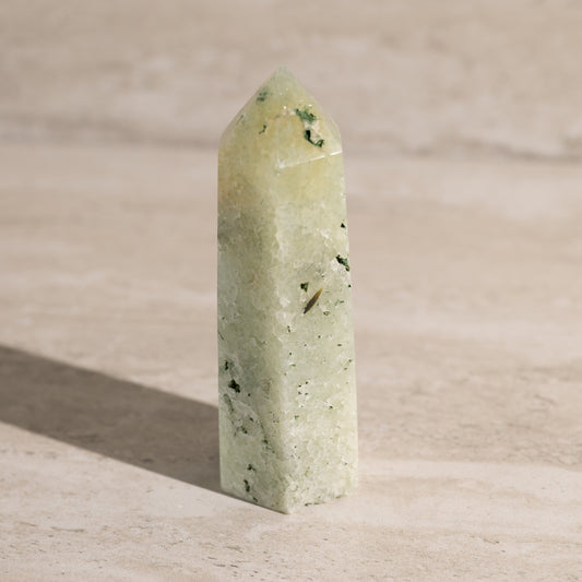 Green crystal pyramid on a beige surface