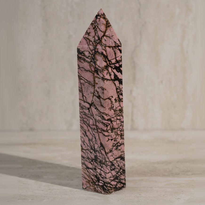 Pink crystal with black vein patterns on a neutral background