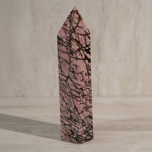 Pink crystal with black vein patterns on a neutral background