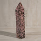 Pink crystal with black vein patterns on a neutral background