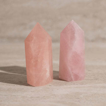 Two pink crystal towers on a wooden surface with a blurred background