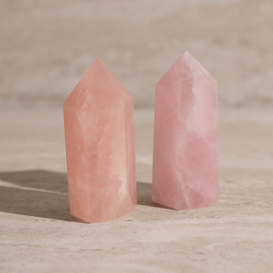 Two pink crystal towers on a wooden surface with a blurred background