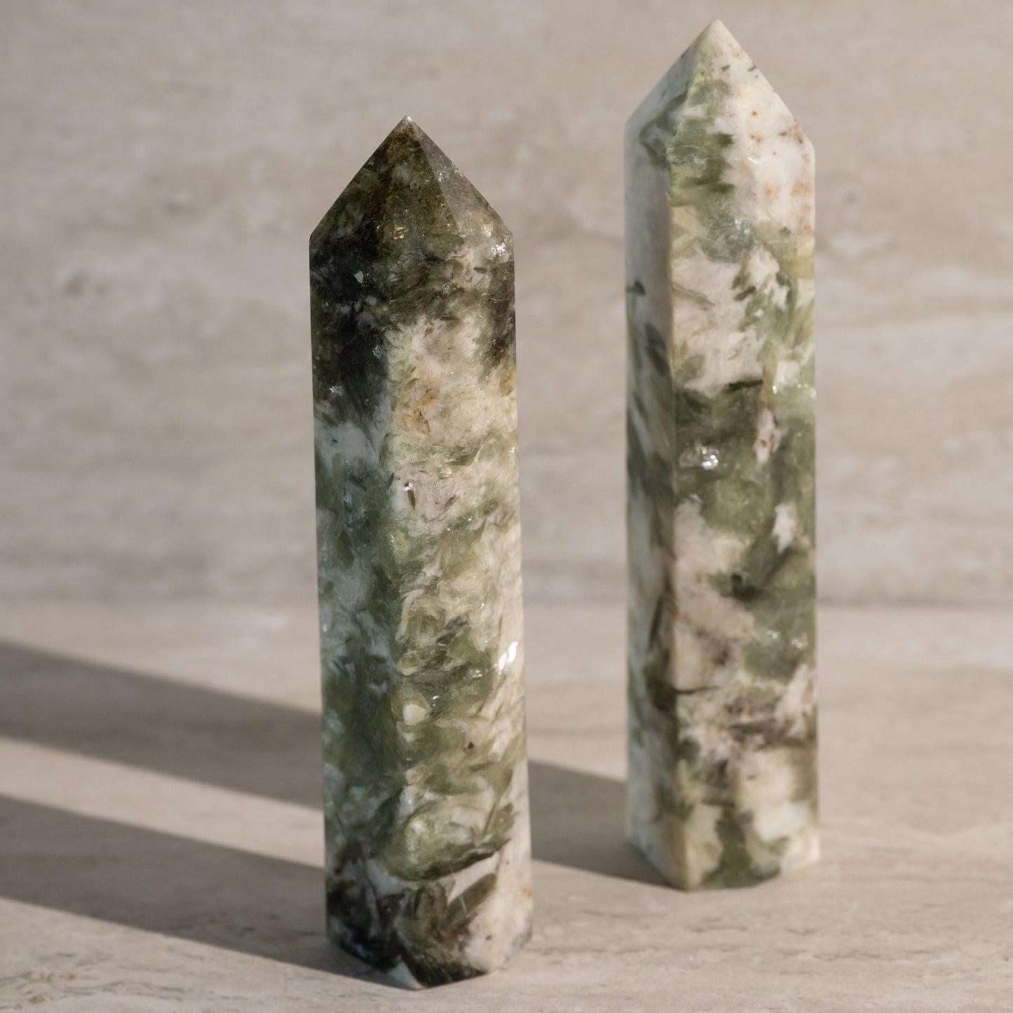 Two green marbleized crystal towers on a textured surface