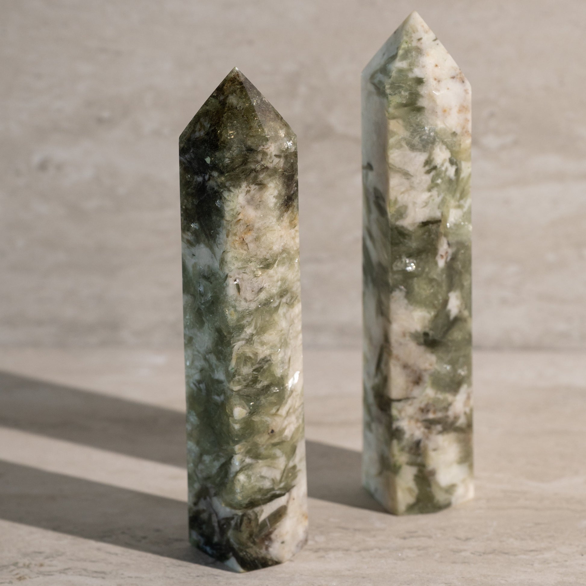 Two green marbleized crystal towers on a textured surface