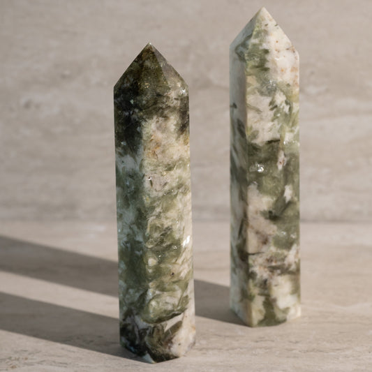 Two green marbleized crystal towers on a textured surface